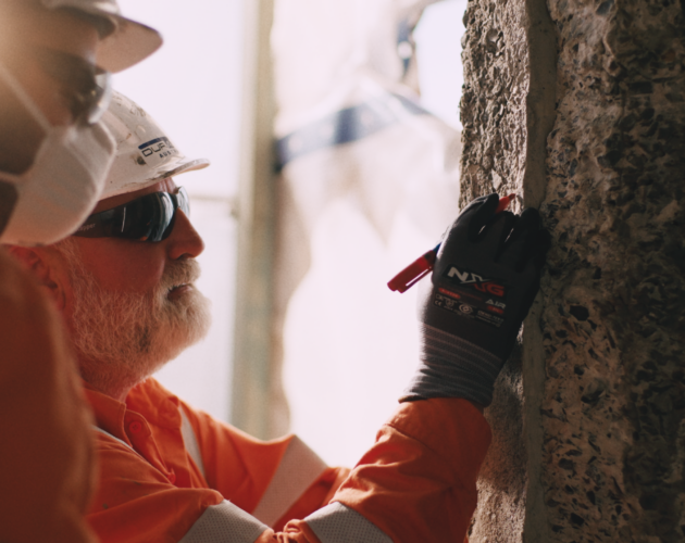 Technician conducting a condition assessment on a deteriorated concrete structure prior to repair works.