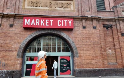 Worker carrying out heritage façade restoration works beneath the Market City entrance.