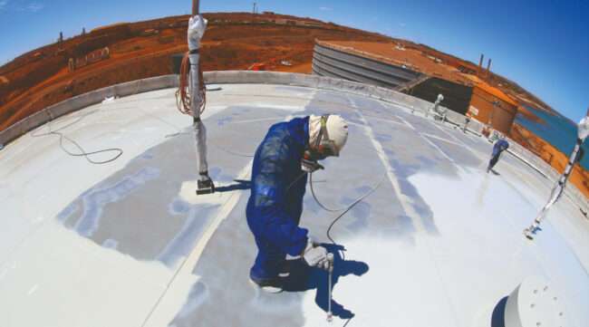 Worker applying a protective waterproofing coating to a concrete structure as part of concrete repair and asset protection works.