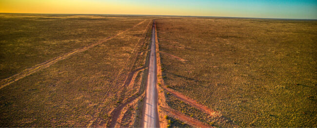 Aerial view of a long unsealed road cutting through remote outback landscape along the Tanami Road in the Northern Territory.