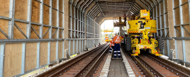 Rail workers and specialised equipment inside the newly installed tunnel structure at Cockle Creek Bridge during rail infrastructure works.