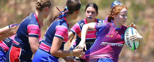 Rugby players in colourful team uniforms grouped together during a match, preparing for play.